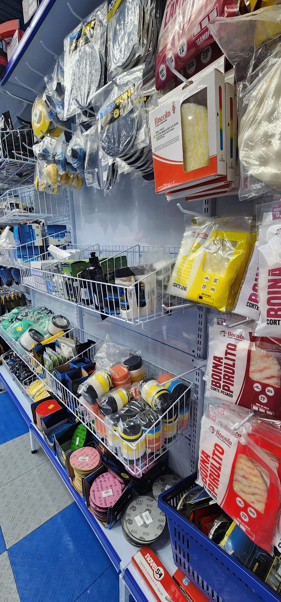 Cestos aramados com gancho na gôndola de parede Gondofort, organizando acessórios automotivos na loja Trixx